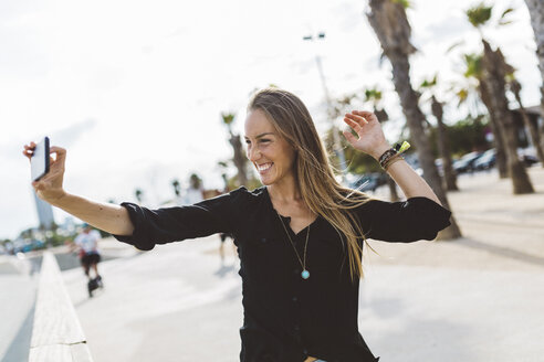 Glückliche junge Frau macht ein Selfie an der Uferpromenade - GIOF01821