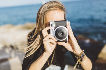Junge Frau fotografiert mit altmodischer Kamera an der Strandpromenade - GIOF01839