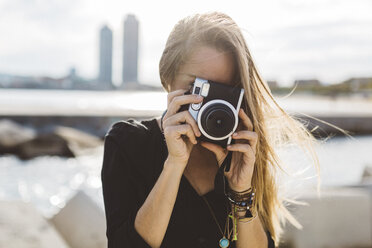 Junge Frau fotografiert mit altmodischer Kamera an der Strandpromenade - GIOF01841