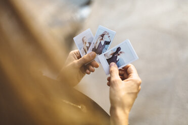 Young woman looking at instant photos of herself - GIOF01844