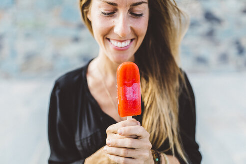 Lächelnde junge Frau mit Eis am Stiel - GIOF01848