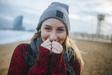 Porträt einer lächelnden jungen Frau am Strand im Winter - KIJF01183