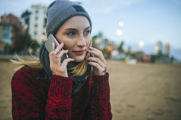 Junge Frau am Strand im Winter mit Mobiltelefon - KIJF01190