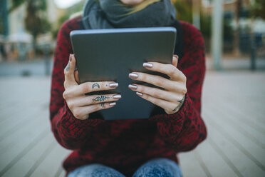 Close-up of tattooed woman's hands with tablet - KIJF01197