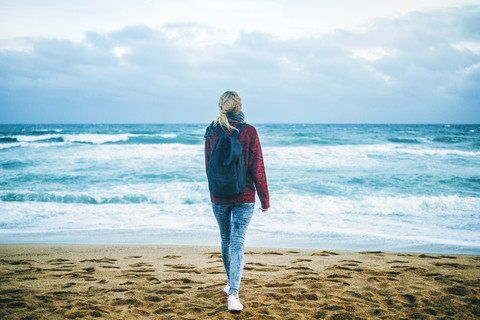 Junge Frau am Meeresufer im Winter, lizenzfreies Stockfoto