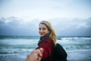 Junge Frau nimmt die Hand eines Mannes am Strand - KIJF01201