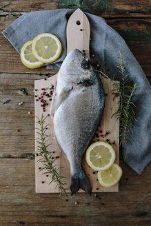 Sea Bream on a wooden board with pepper and rosemary - GIOF01850