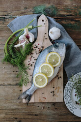 Sea Bream on a wooden board with spices and herbs - GIOF01852