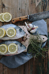 Sea Breams on a wooden board with spices and herbs - GIOF01853