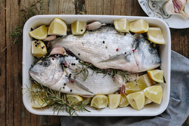 Sea Breams in baking dish with fresh lemon, rosemary and pepper - GIOF01862