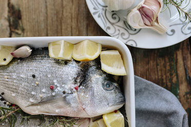 Sea Breams in baking dish with fresh lemon, rosemary and pepper - GIOF01863