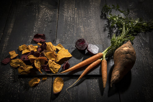 Gemüsechips aus Karotten, Süßkartoffeln und Roter Bete auf dunklem Holz - MAEF12135