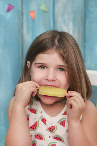Porträt eines kleinen Mädchens, das einen Zitroneneislutscher isst, lizenzfreies Stockfoto