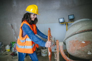 Frau arbeitet mit einem Betonmischer auf einer Baustelle - KIJF01215