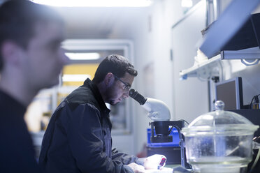 Man using a microscope in a sensor technology plant - SGF02112