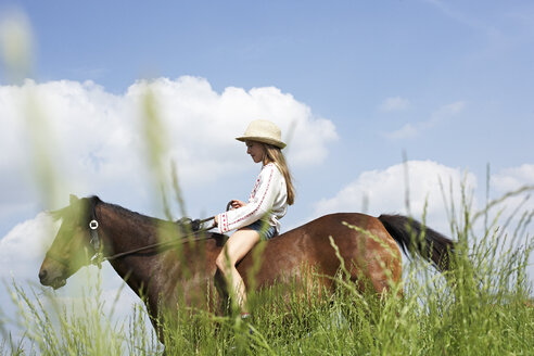Mädchen reitet Pferd auf Wiese - FSF00782