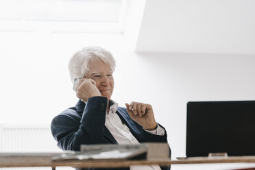 Lächelnder älterer Geschäftsmann am Telefon in seinem Büro - KNSF00999
