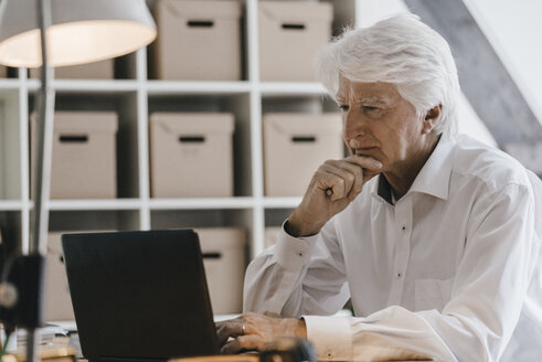 Ein älterer Geschäftsmann arbeitet in seinem Büro am Laptop - KNSF01006
