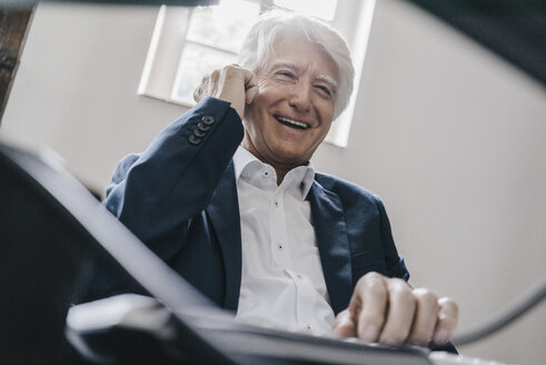 Porträt eines lachenden älteren Geschäftsmannes am Telefon in seinem Büro - KNSF01009
