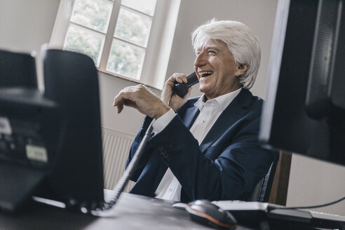 Laughing senior businessman on the phone in his office - KNSF01010