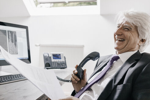 Laughing senior businessman on the phone in his office - KNSF01023