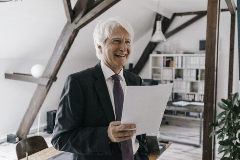 Porträt eines lächelnden älteren Geschäftsmannes mit Dokument in seinem Büro - KNSF01024