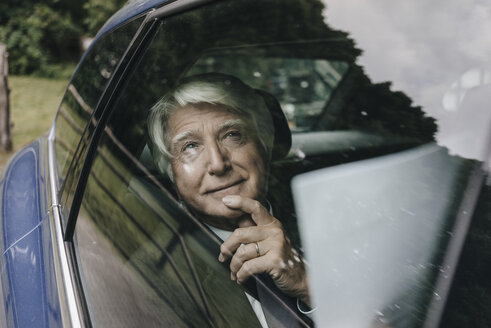 Portrait of senior businessman looking through car window - KNSF01027