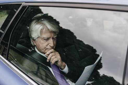 Senior businessman reading documents in a car - KNSF01028