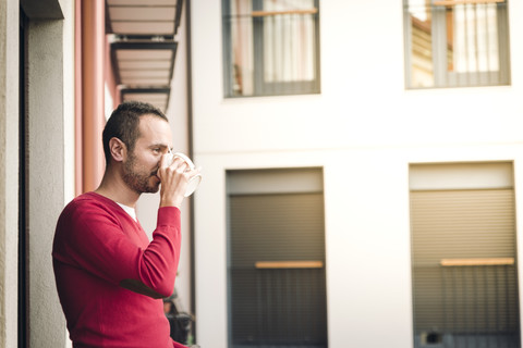 Mann auf Balkon trinkt Kaffee, lizenzfreies Stockfoto