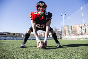 American-Football-Spieler mit Helm und Ball auf einem Sportplatz - ABZF01925