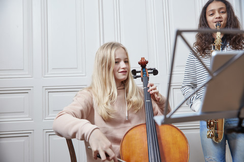 Zwei Mädchen spielen zusammen Cello und Saxophon, lizenzfreies Stockfoto