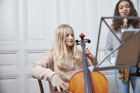 Zwei Mädchen spielen zusammen Cello und Saxophon - RHF01807