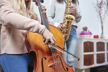 Zwei Mädchen spielen zusammen Cello und Saxophon - RHF01809