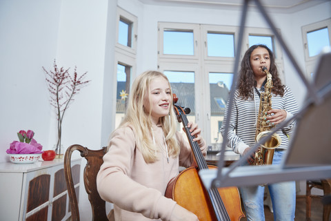 Zwei Mädchen spielen zusammen Cello und Saxophon, lizenzfreies Stockfoto