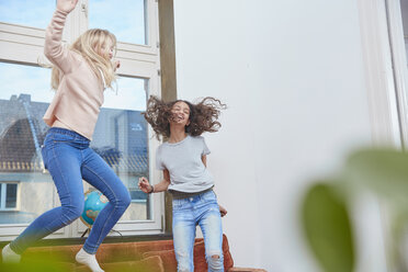 Zwei begeisterte Mädchen springen und tanzen zu Hause - RHF01812