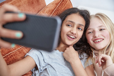 Zwei glückliche Mädchen schauen auf ihr Smartphone - RHF01819