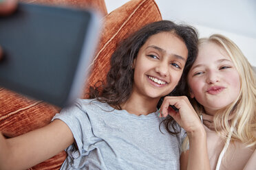 Zwei glückliche Mädchen auf der Couch machen ein Selfie - RHF01820