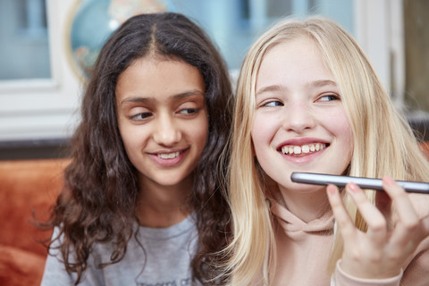 Two happy girls using smartphone stock photo