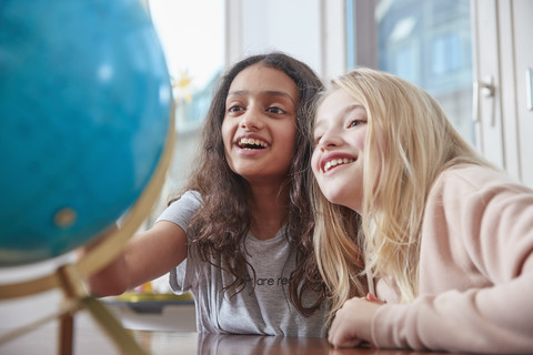 Two excited girls looking at globe stock photo