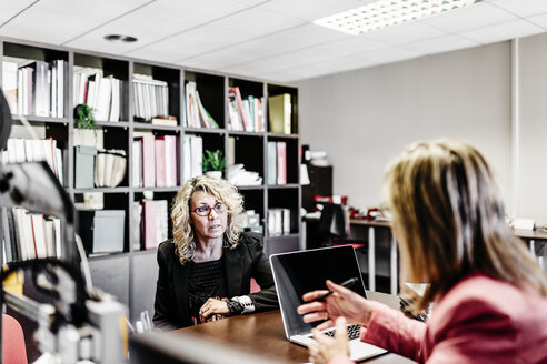 Zwei Geschäftsfrauen im Gespräch am Schreibtisch im Büro - JRFF01182