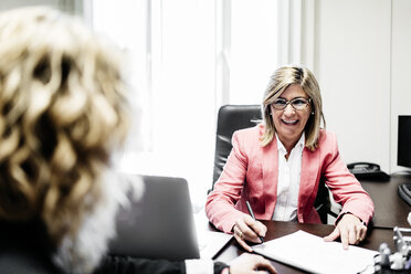 Two businesswomen working on document in office - JRFF01185