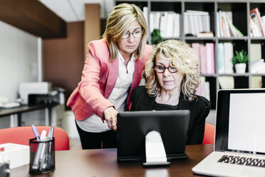 Zwei Geschäftsfrauen mit Laptop am Schreibtisch im Büro - JRFF01191