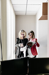 Zwei Geschäftsfrauen arbeiten gemeinsam an einem Dokument im Büro - JRFF01203