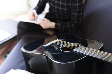 Gitarre auf der Couch und Mann macht sich Notizen - FMOF00151
