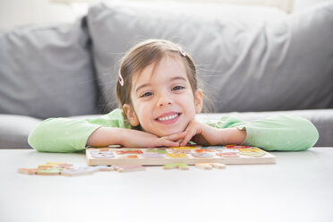Porträt eines lächelnden kleinen Mädchens mit Holzbuchstaben zu Hause - LVF05872