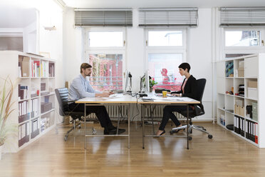 Colleagues working at desk in office - FKF02136