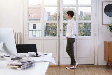 Frau steht am Fenster im Büro - FKF02139