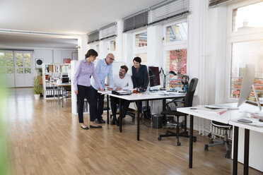 Colleagues working together at desk in office - FKF02190