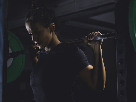 Junge Frau hebt eine Langhantel im Power Rack - MADF01341