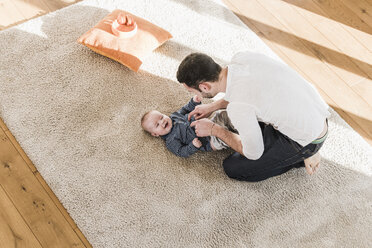 Father changing diapers and playing with his baby son - UUF09869
